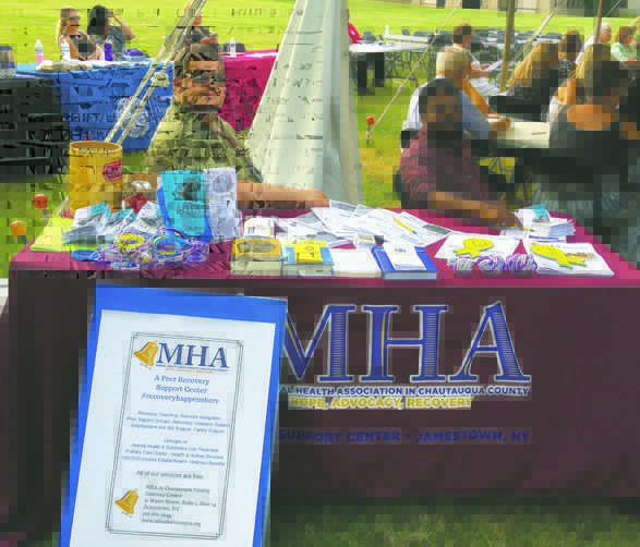 OBSERVER Photos by J.M. Lesinski: MHA Certified Peer Specialist Justin Jimenez, pictured seated at left, spoke to the OBSERVER about programs and services offered by the Mental Health Association in Chautauqua County at the community event Tuesday evening.
